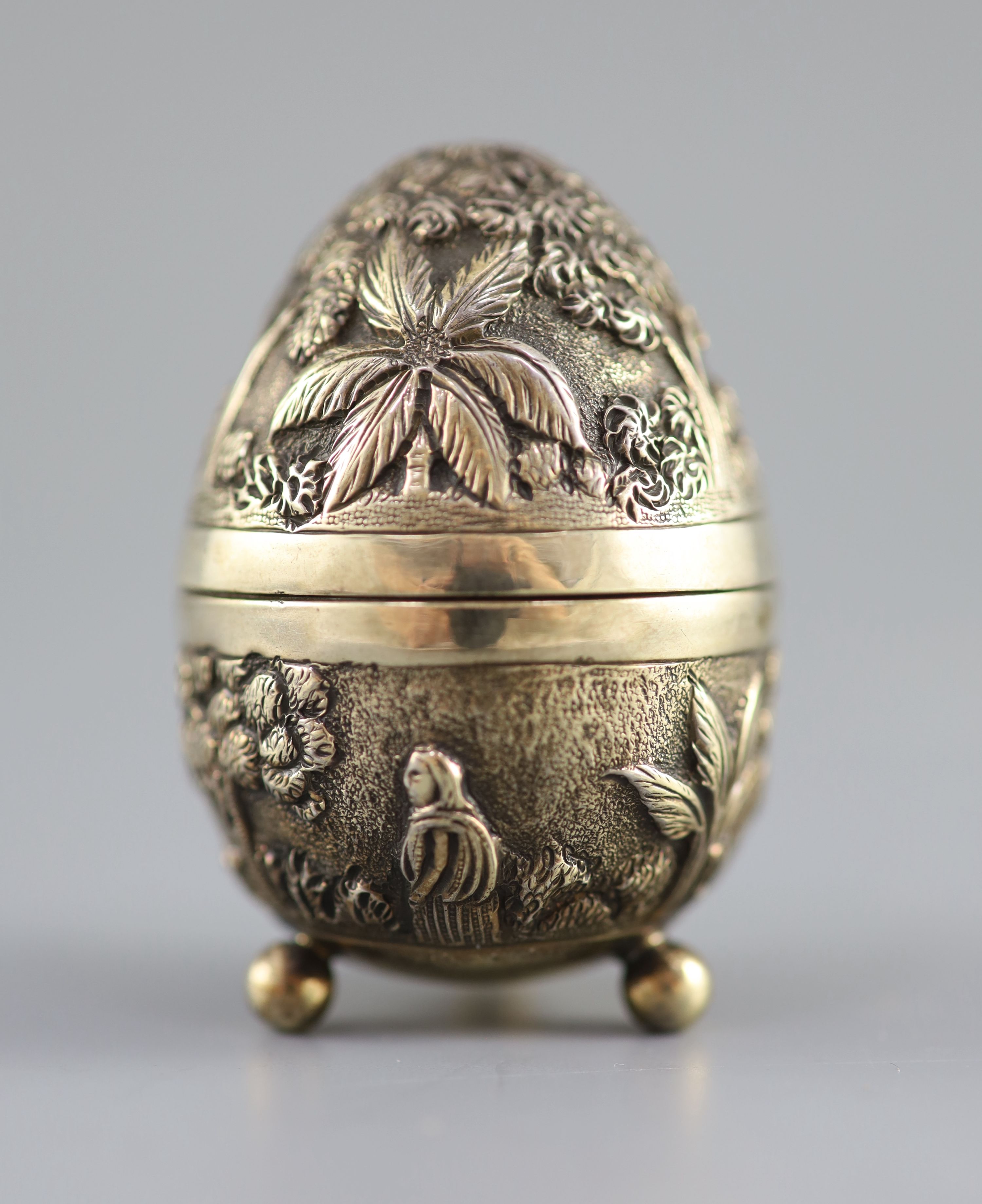 A graduated pair of Edwardian novelty silver gilt condiments, modelled as eggs, with bird's nest interior including two 'marbled' eggs